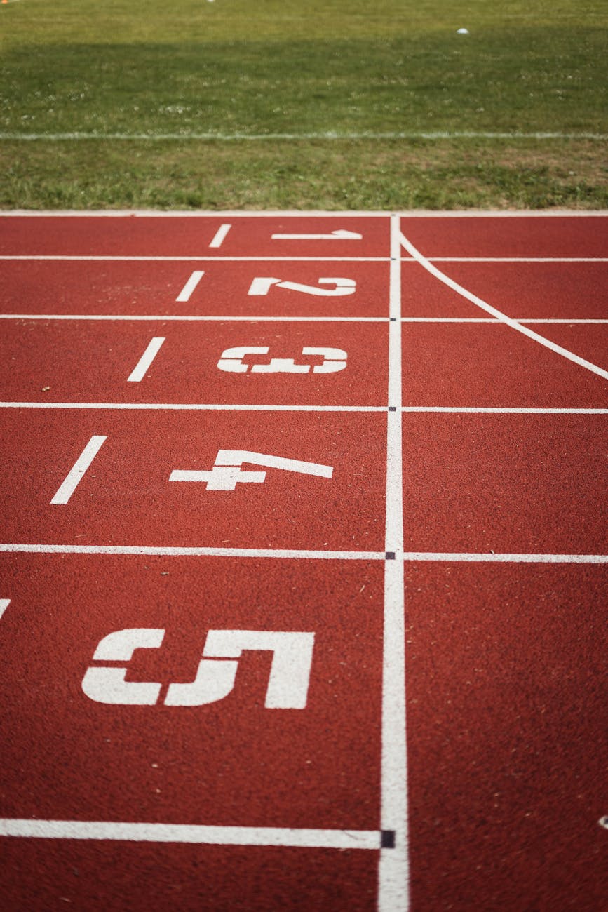 Close-up of a running track with numbered lanes, featuring red rubber surface and green grass in the background. Indicates ranking to go with Item Comparison in Data Storytelling.